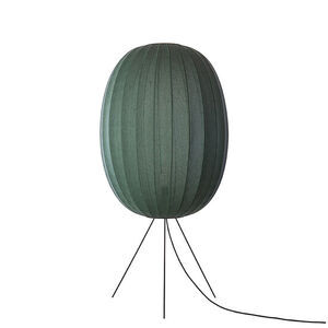 Oval mørkegrøn lampe med strikket overflade på trefodsstativ.